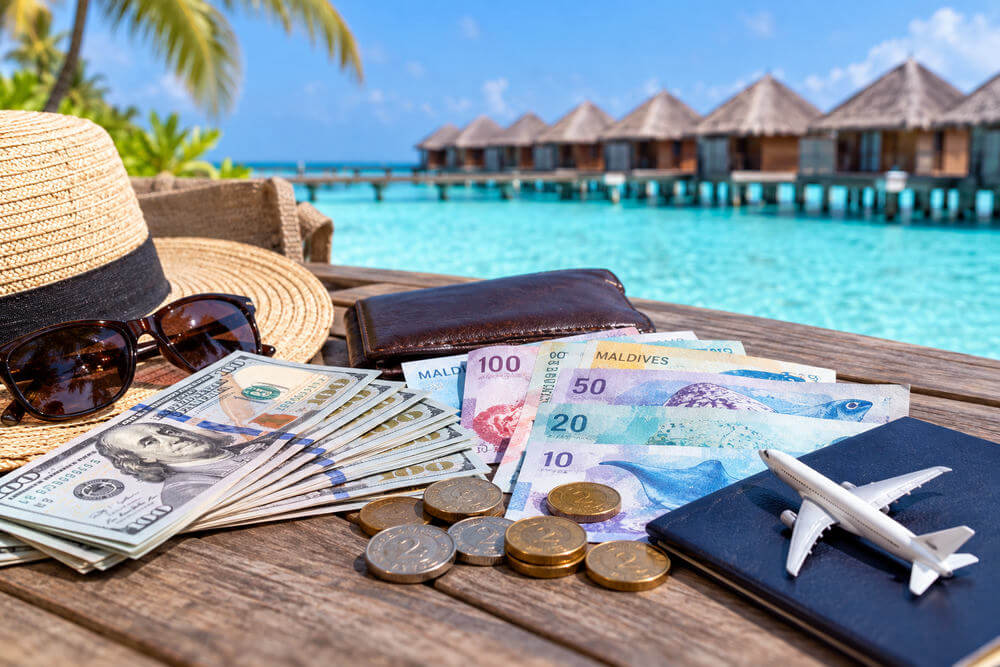 Banknoty dolarowe i rufiyaa obok portfela na malediwskim tarasie